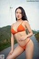 A woman in an orange bikini posing for a picture.