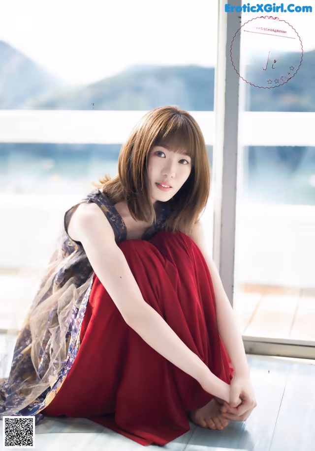 A woman in a red dress sitting on the floor.