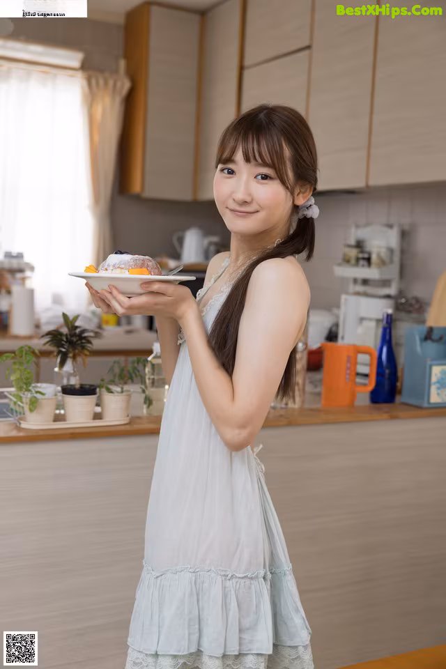 A woman holding a plate of food in a kitchen.