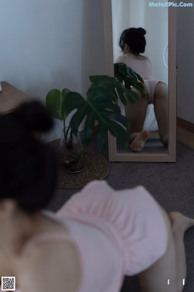 A woman sitting on the floor in front of a mirror.
