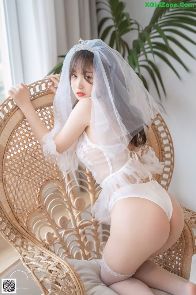a woman in a white lingerie sitting on a wicker chair