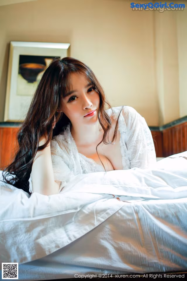 A woman laying on top of a bed in a white robe.