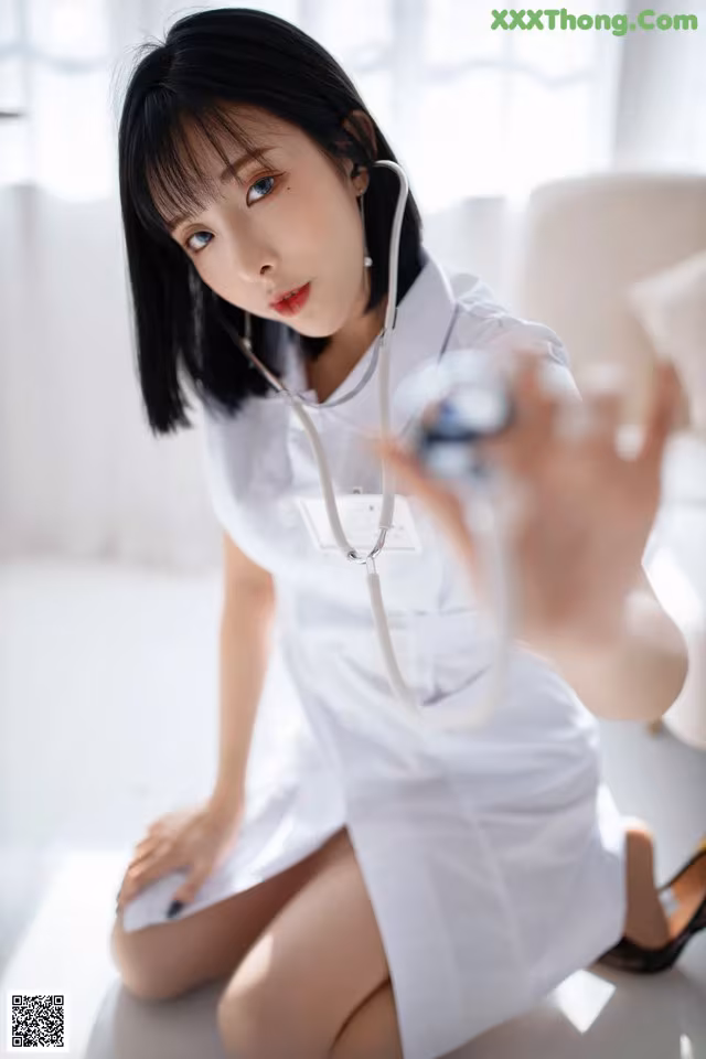 A woman in a white lab coat holding a stethoscope.