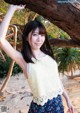 A young woman leaning against a tree on the beach.