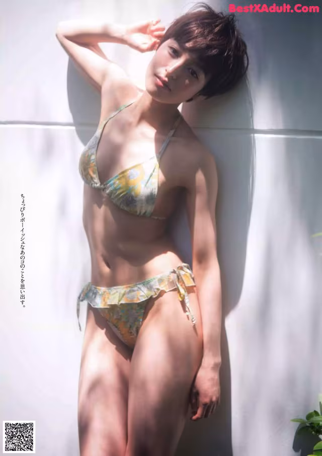A woman in a bikini leaning against a wall.