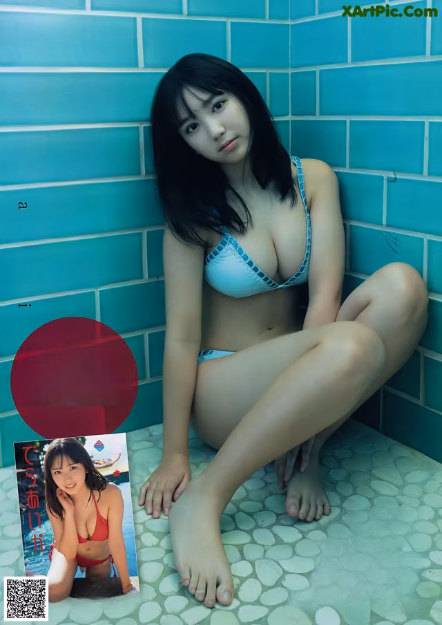 A woman in a blue bikini sitting on a tiled floor.