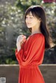 A woman in a red dress standing on a bridge.