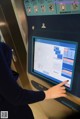 A woman is using a touch screen at an elevator.