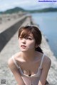 A woman sitting on the edge of a pier by the water.