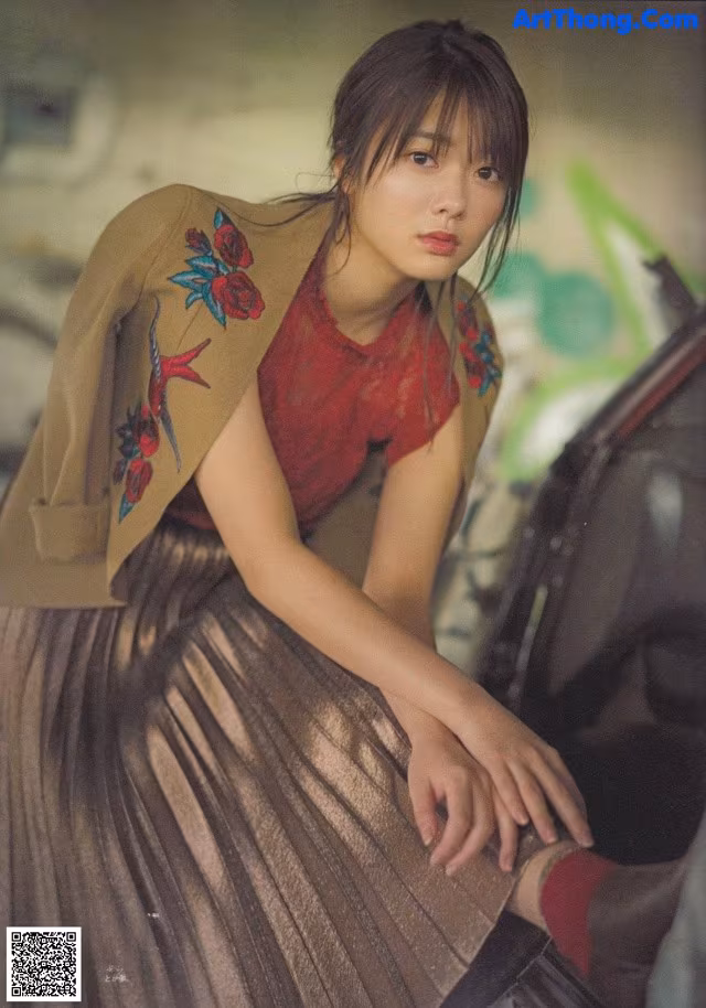 A woman sitting on the ground next to a car.