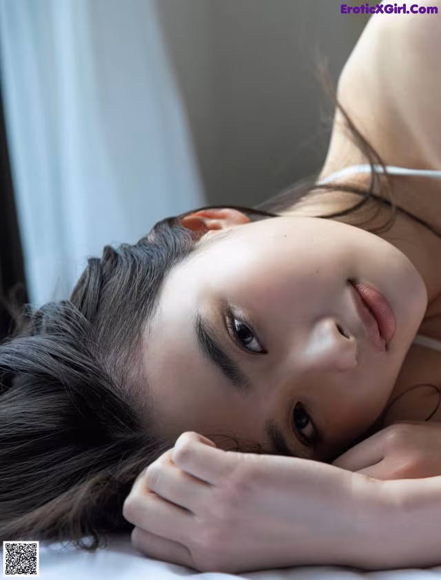 A woman laying on a bed with her head resting on her hands.