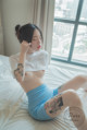 A woman sitting on a bed with a tattoo on her arm.